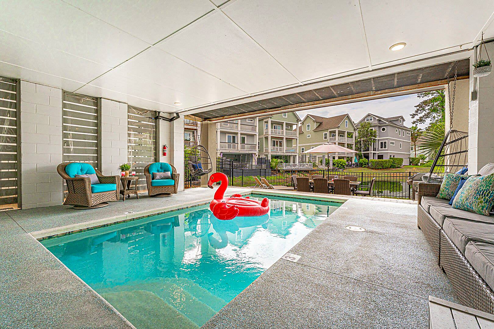 Heated private pool under the house at 122 Sandcastle Court, with the roll-up door open to the lagoon beyond