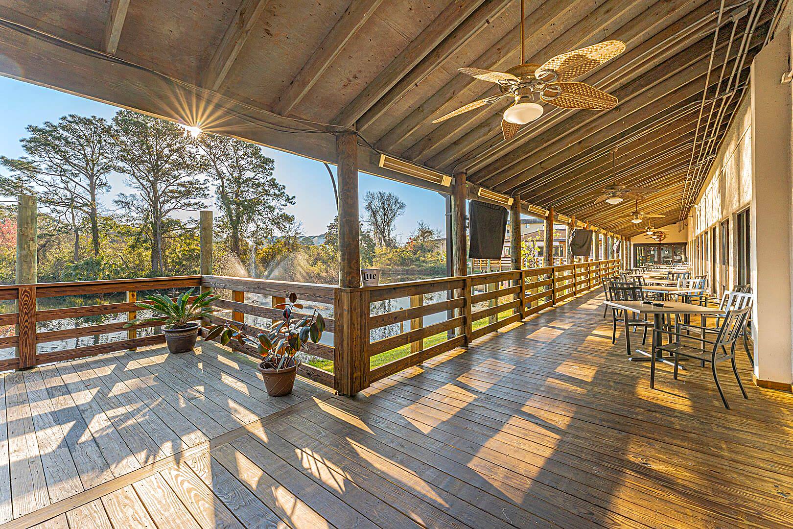 Long covered wooden deck with ceiling fans overlooking a lagoon and fountain at 40 Folly Field Road, Hilton Head Island